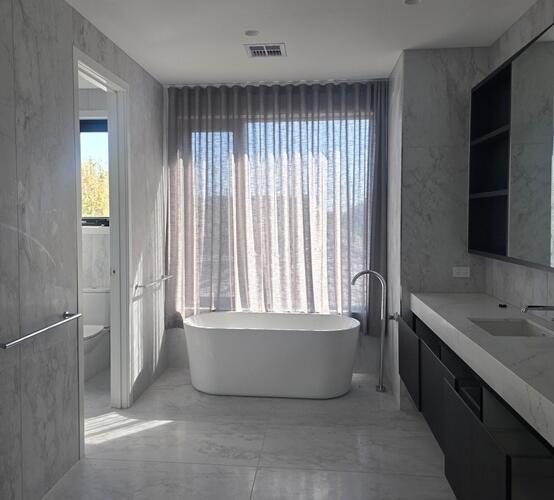 Spa-like bathroom with wavefold sheer tucked behind bathtub