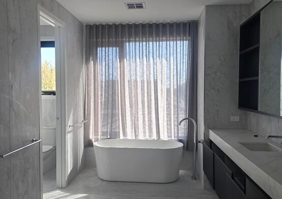Spa-like bathroom with wavefold sheer tucked behind bathtub