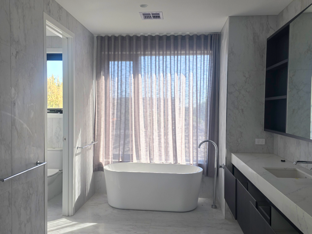 Spa-like bathroom with wavefold sheer tucked behind bathtub