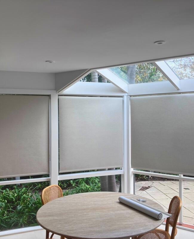Bay of windows in Beaumaris dining room with roller blinds for light control and privacy installed by Fabric Creations